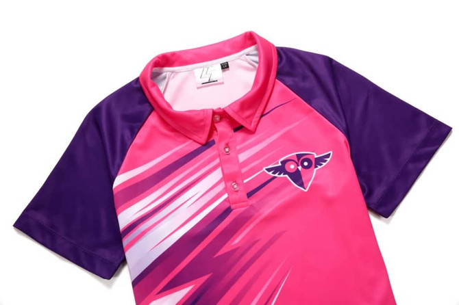 A women's polo in pink and purple with a logo, featuring a smaller collar and dynamic graphic design.
