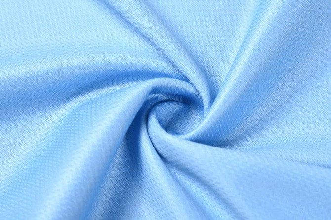 A piece of light blue fabric with a textured surface, arranged in a spiral pattern.