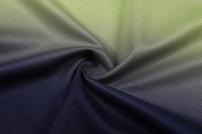 A textured fabric featuring a gradient of green to dark blue, showcasing a hexagonal pattern.
