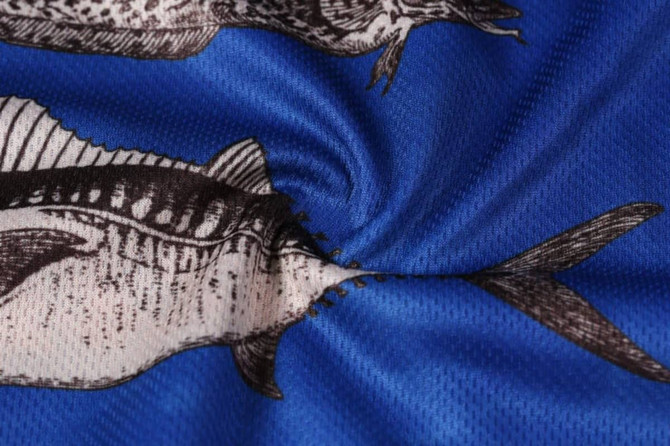 A close-up of a blue fabric featuring printed fish illustrations, showcasing a textured pattern.
