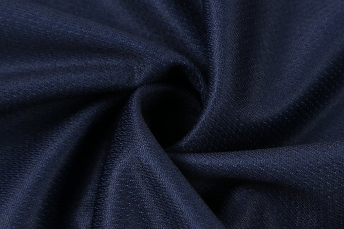 A close-up of navy fabric, showcasing a smooth texture with subtle patterns. The material is gathered in a spiral shape.