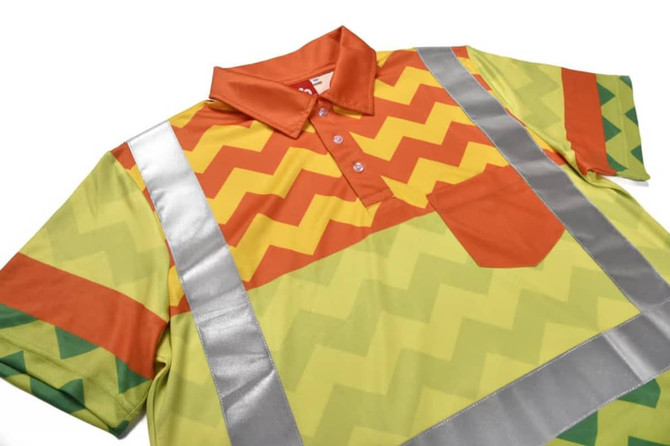 A brightly coloured polo shirt featuring a zigzag pattern in yellow, orange, and green, with reflective tape accents.