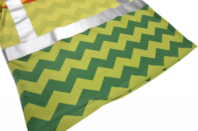 A reflective safety garment in vibrant yellow with green zigzag patterns and silver reflective tape.