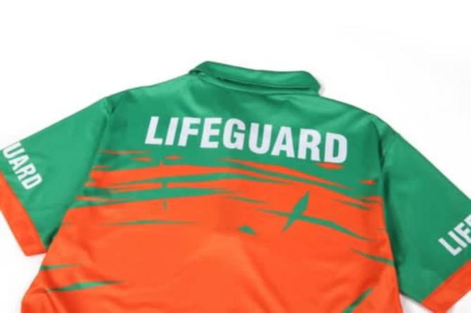 A quarter zip lifeguard uniform in green and orange with a logo on the back and sleeves.