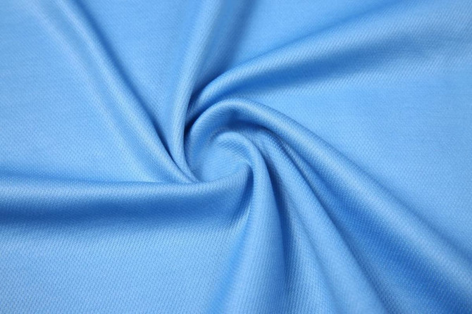 A light blue fabric with a smooth texture, arranged in a swirl pattern, showcasing its stretch and softness.