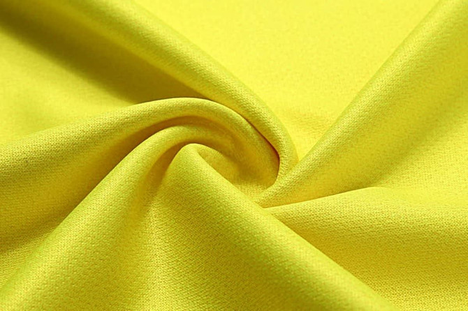 A close-up of fluorescent yellow fabric, showcasing a smooth texture and slight sheen. The fabric has a subtle pattern.