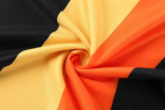 A close-up of fabric featuring black, yellow, and orange stripes, with a smooth, swirling texture.