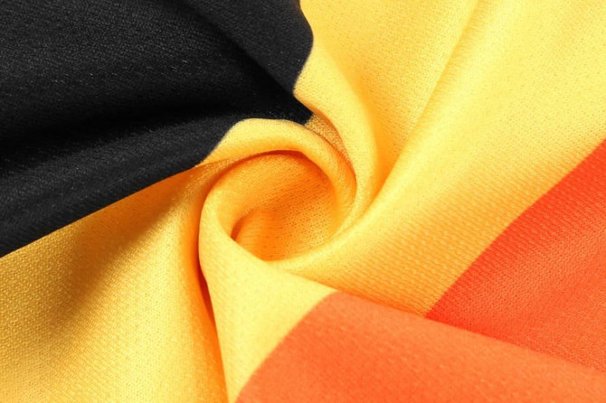 A close-up of a fabric featuring black, gold, and red colours, arranged in a swirling pattern.