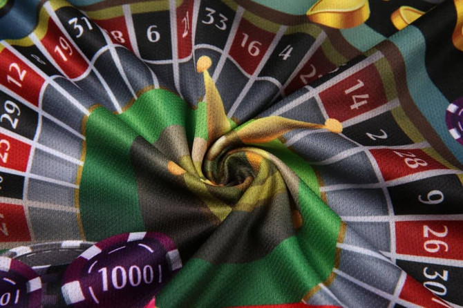 A vibrant fabric featuring a roulette wheel, poker chips, and bright colours in a swirling pattern.