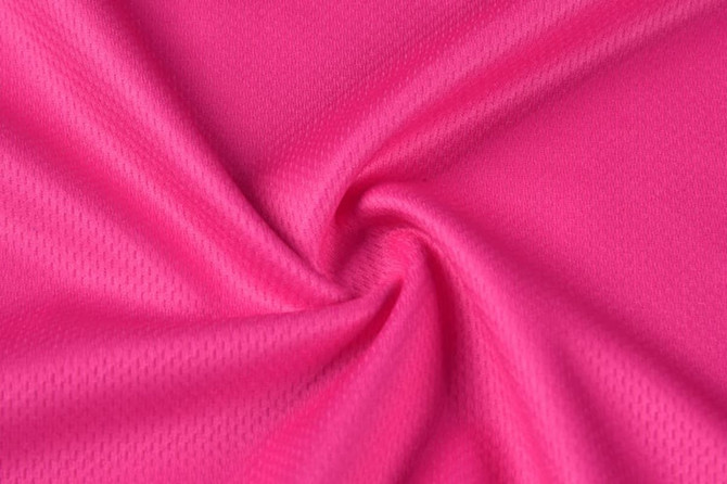 A textured fabric in vibrant pink, featuring a smooth, stretchy weave. It has a light and breathable appearance.