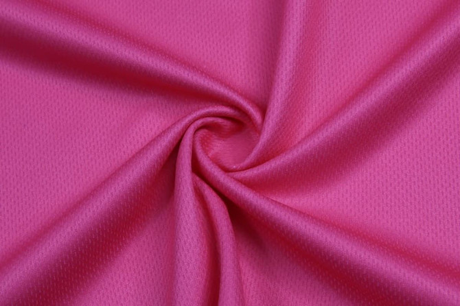 A pink basketball vest featuring a mesh fabric with a textured pattern and a logo.