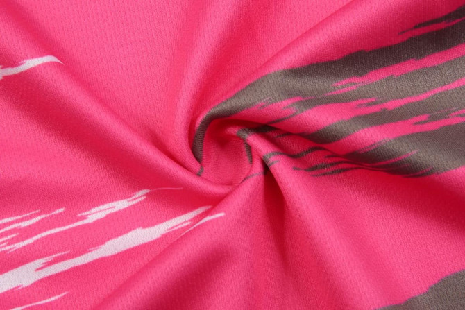 A close-up of a pink fabric with abstract grey and white patterns, showcasing the texture and colour of the material.