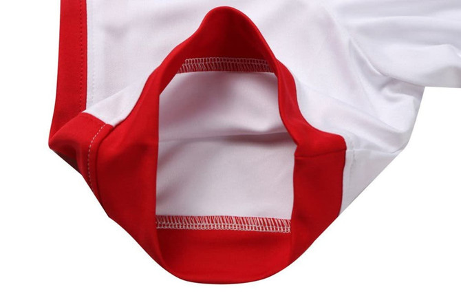 A close-up view of a cut-and-sew garment in white fabric with red accents and stitching.
