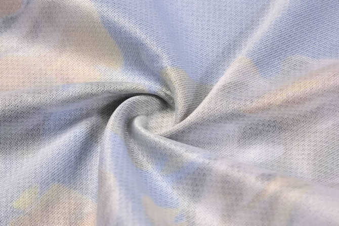 A fabric swirl featuring a light blue background with soft, abstract patterns in pastel colours. It has a smooth texture.