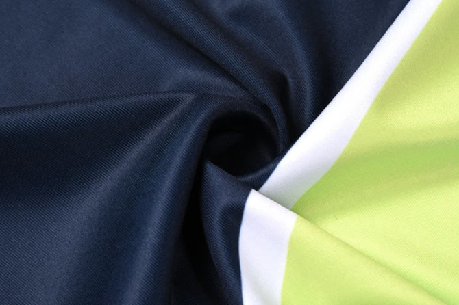 A fabric swatch featuring a swirl of navy blue and vibrant green materials, with white accents.