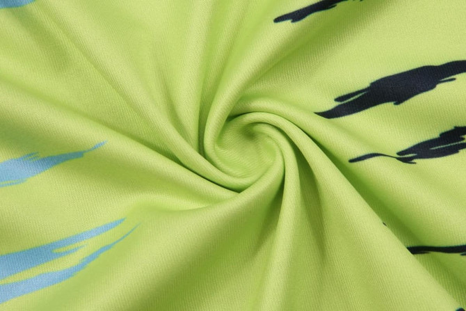A green fabric featuring a swirling pattern with silhouettes in black and blue. It has a smooth texture.