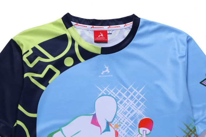 A blue and green soccer polo featuring abstract designs and a logo. The collar is black with a subtle pattern.