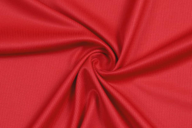 A vibrant red fabric with a textured surface, arranged in a spiral pattern.