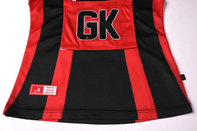 A netball polo in red and black with a logo and a "GK" label.