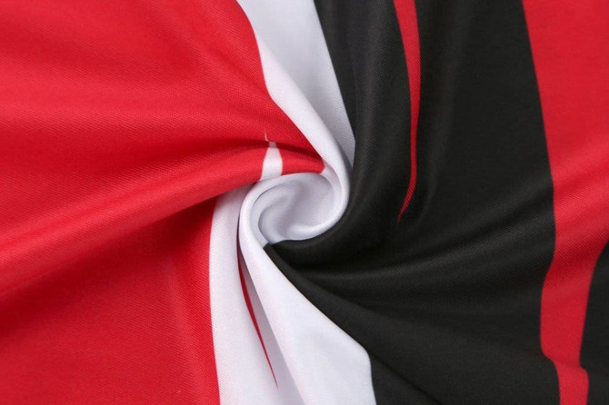 A fabric featuring red, black, and white stripes, displaying a smooth, spiralled texture.