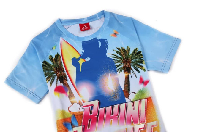 A women's tee shirt with a blue background, featuring a surf theme and palm trees, and a silhouette of a person.