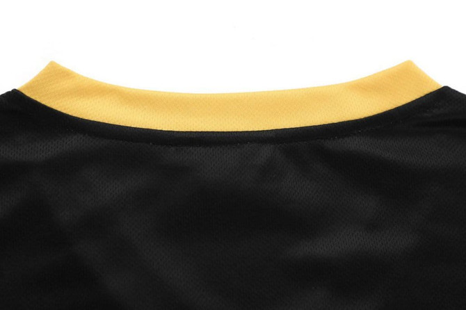 A black V-neck tee with a yellow collar featuring a logo on the back.