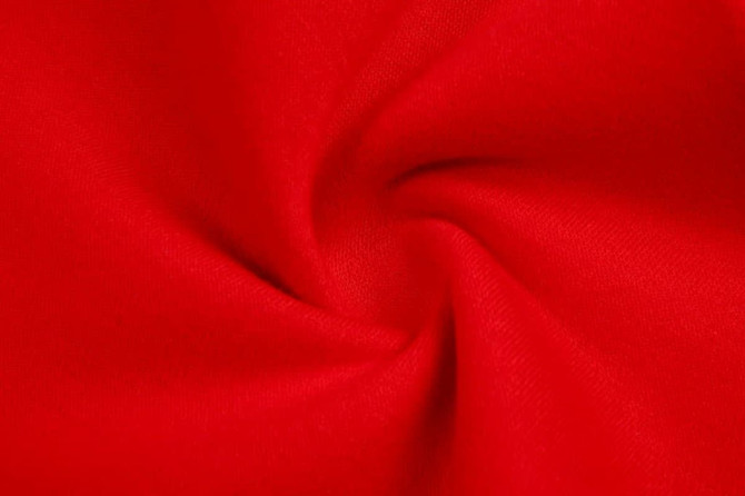 A red fleece fabric displaying a smooth, twisted texture. The material is soft and durable.