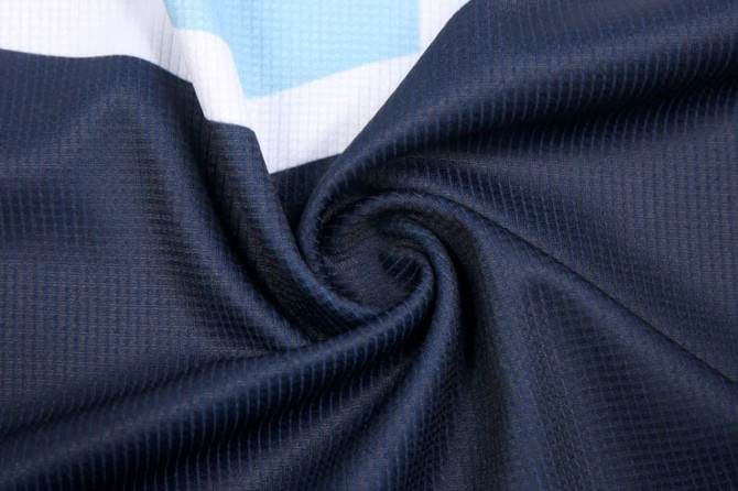 A close-up of a fabric swirl featuring navy blue and white patterns, showcasing a textured material.