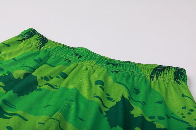 Bright green shorts with a camouflage pattern featuring an elastic waistband. The shorts have a logo on the side.