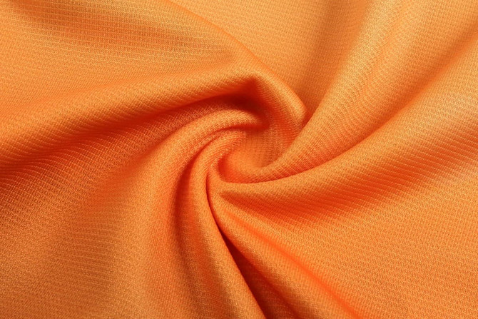 A swirl of bright orange fabric, featuring a textured pattern. The material appears lightweight and smooth.