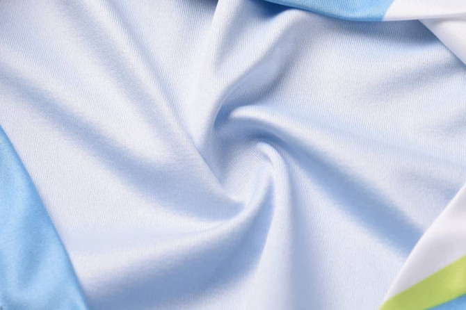 A light blue fabric with a smooth texture, featuring folds and creases. The material appears soft and flexible.