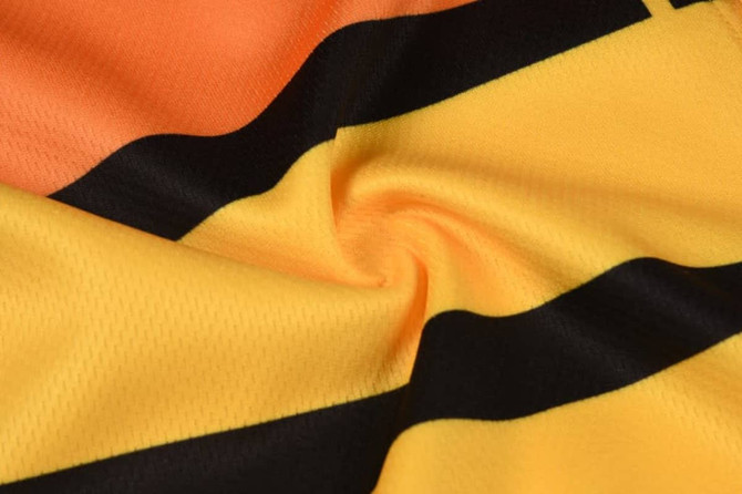 A close-up of a fabric featuring orange and yellow with black stripes, showcasing a textured design.