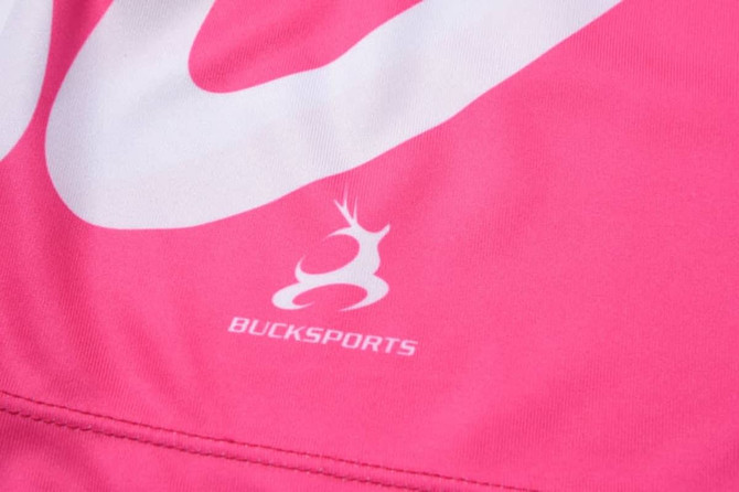 A close-up of a pink fabric with a white logo and the word "BUCKSPORTS" printed on it.