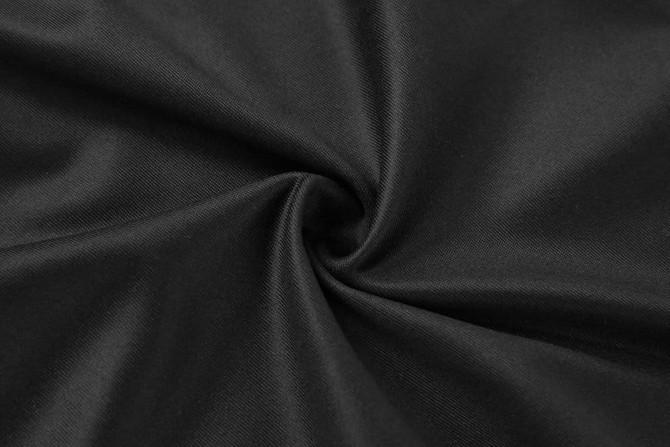 A black fabric displayed in a swirling pattern, showcasing its smooth and soft texture.