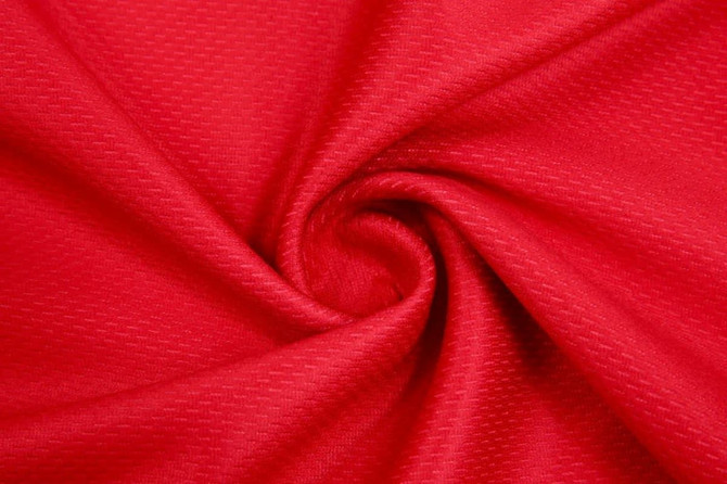 A close-up view of fabric in a vibrant red colour with a textured pattern.