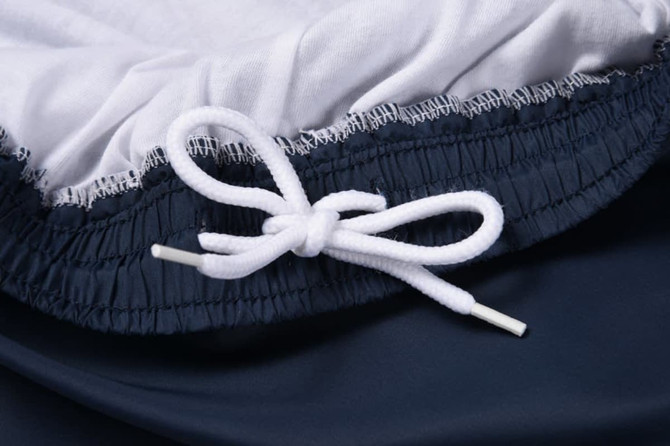 A close-up of a navy product featuring a white drawstring and cotton lining at the waistband.