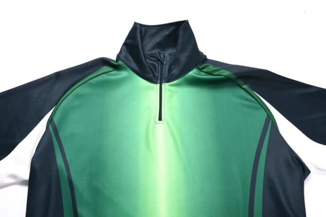A green and navy sublimated pullover featuring a half-zip collar and long sleeves, with a logo on the front.