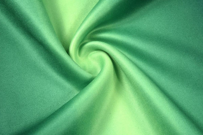 A smooth fabric featuring a gradient of vibrant green shades, showcasing a silky texture.