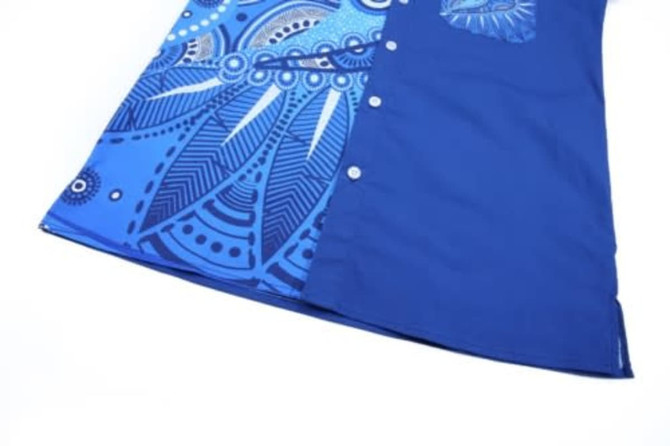 A blue cotton shirt featuring intricate patterns in various shades of blue and a small pocket, with buttons on the front.