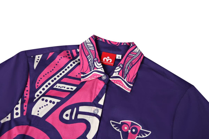 A purple school shirt featuring vibrant pink patterns and a collar with a colourful design. It has a logo on the collar.