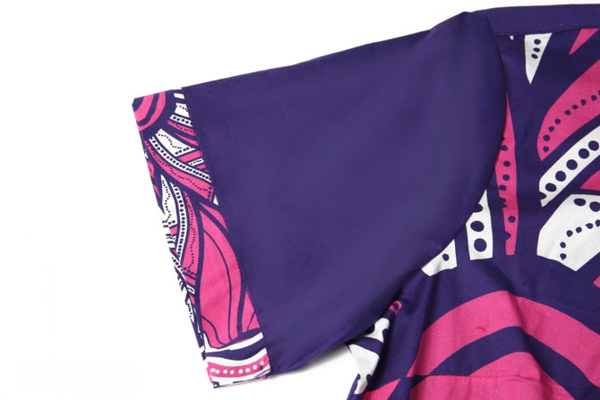 A purple school shirt featuring a vibrant pink pattern on one sleeve and a contrasting solid colour on the other.