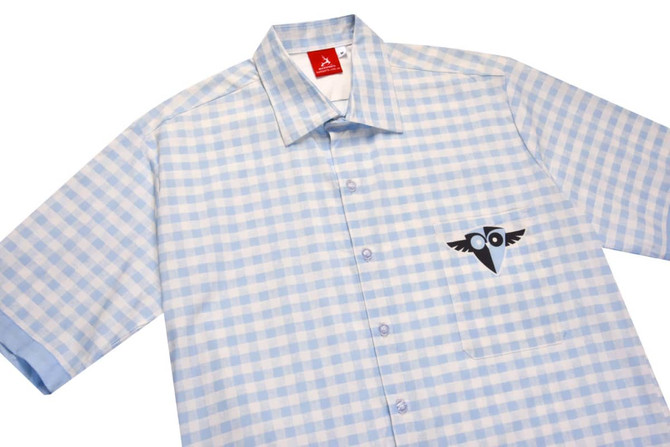 A blue and white checked school wear shirt with short sleeves and a logo on the chest.