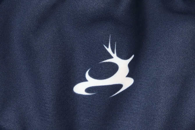 A close-up of a navy fabric featuring a white logo with a stylised deer design.