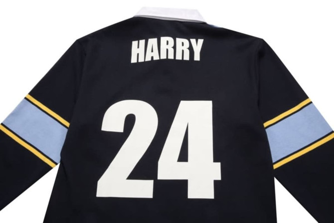 A black sports jumper featuring a white number "24" and a name on the back, with blue and yellow stripes on the sleeves.