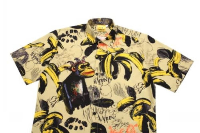 A short-sleeve shirt featuring a playful banana and monkey print in yellow and black tones on a beige background.