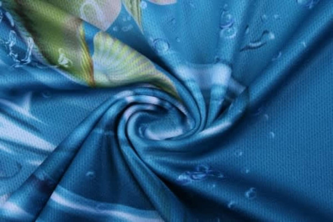 A swirling fabric in shades of blue, featuring aquatic designs and a smooth texture, with a logo visible.