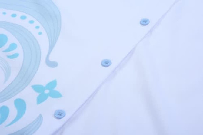 A white shirt featuring a blue floral design, with light blue buttons along the placket.