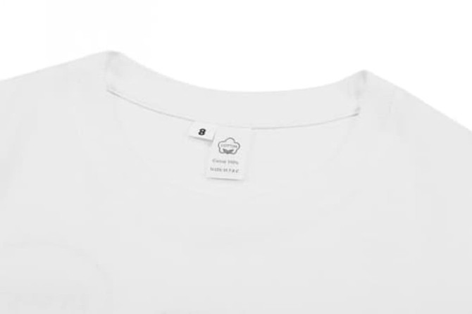 A white cotton t-shirt with a tag at the neckline, featuring a simple design. It includes a logo.