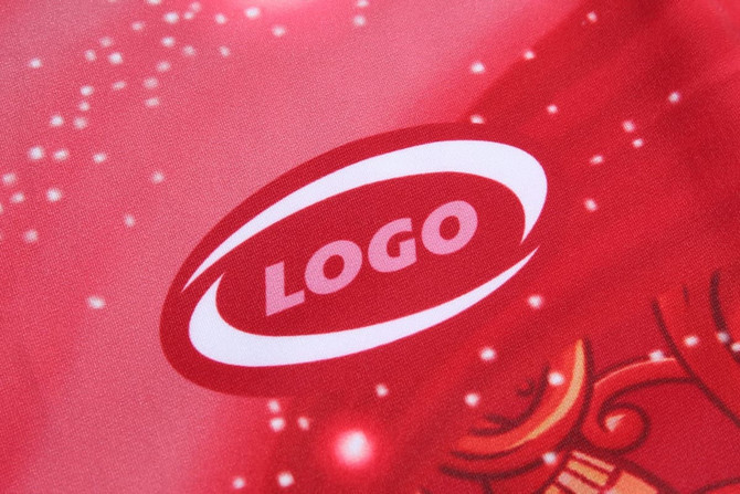 A close-up of a red fabric featuring a logo with a subtle design, suitable for a sports uniform.