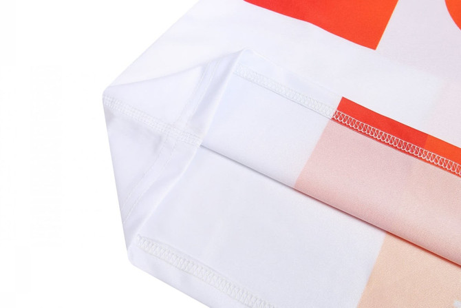 A close-up of a white sports uniform featuring vibrant orange and peach patterns with neat stitching edges.